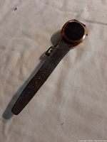 Vintage Timex wristwatch with gold-tone round case, red display, and brown leather strap laid flat on light surface.