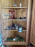 Full view of three shelves with multiple curios including glassware, figurines, toy tractors, and various small collectibles.