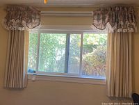 Curtain panels fully extended covering window with floral valence above