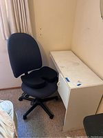 Desk and chair side view showing white desk surface with stains and the blue office chair next to it.