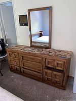 Full dresser with mirror above, dresser top covered with floral fabric, wood carved details on drawers