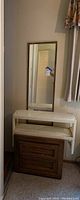 Photo of rectangular mirror hung on wall with white plastic shelf and wooden nightstand beneath, showing dimensions and condition.