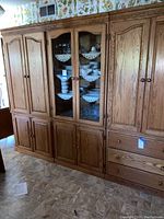Front view of the oak hutch cabinet showing central curio cabinets with glass doors and flanking wood door cabinets with drawers below.