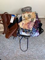 Overview of purses and scarves piled together showing multiple fabric scarves and purses including a brown tote