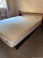 Full queen bed with mattress in a room near a window showing mattress and bed frame.