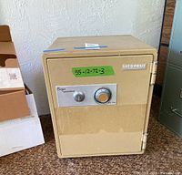 Front view of beige Soya safe deposit box with combination dial and key lock, with green label 55-12-72-3 on door.