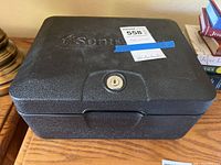 Closed black Sentry safe box on wooden surface showing front lock and embossed logo.