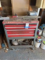 View of the red Craftsman tool chest with dirt and various items stored underneath