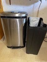 Stainless steel step pedal trash bin with black plastic removable liner bin beside it on floor.