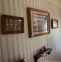 Three wall-hung items and a wooden shelf with decorative figures beneath