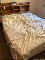 Bed fully assembled with mattress and white fitted sheet.