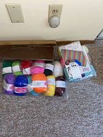 Image showing multiple skeins of yarn in assorted colors inside plastic packaging with craft kit on the side.
