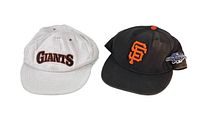 Photo of two vintage San Francisco Giants hats: one white, one black with logo and patch
