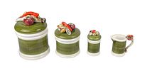 Four green and white ceramic kitchen canisters with decorative vegetable-themed lids, arranged in ascending size from right to left. Includes a small creamer or sugar bowl.