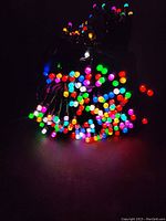 Close-up of coiled black wire string light with tightly packed, brightly lit multi-colored LEDs against dark background.