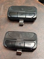 Two black programmable garage door remotes side by side showing the front with three buttons each.