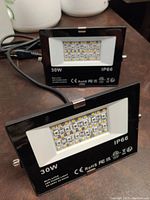 Two black 30W flood lamps with LED arrays and IP66 rating visible on front.