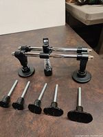 Wide shot of the complete dent pulling tool kit with slide hammer and six puller pins laid out on a brown surface.