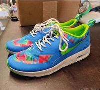 Side angle profile of the right and left Nike Air Max Thea running shoes showing colorful design and white sole