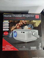 Box showing RCA home theater projector, features Bluetooth, 2 HDMI inputs, HD 720p resolution, and built-in rechargeable battery