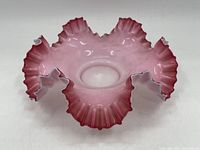 Angled front view of antique cranberry glass dish showing detailed ruffled edges and overall flared shape with cranberry pink color.