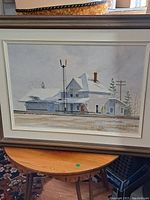 Full view of framed oil painting depicting a house and railroad signal in winter snow.