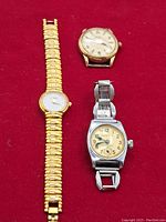 Photo of the 3 wrist watches on red background showing 2 gold-tone watches and 1 silver-tone watch with damaged band
