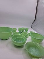 Front view of all jadeite pieces: bowls, cups, saucers, and cordial glasses