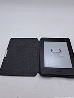 Amazon Kindle Paperwhite e-reader inside a protective gray fabric cover, showing device and cover.