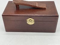 Front view of wooden box with brass clasp and raised handle on lid.