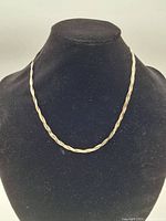 Full view of the twisted rope necklace displayed on a black bust stand, showing its tri-color shaded finish in silver, gold, and rose tones.