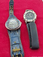 Two men's wristwatches displayed on a red background, showing the Rideau Birks watch with blue leather strap and the Terramax watch with nylon strap.