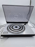 Front angled view of Beogram 1602 turntable with hinged transparent dust cover open, showing platter and tonearm.