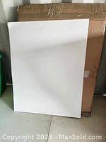 Single white bristol board leaning against a cardboard box, showing the size and surface of the board.