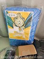 Blue 15x15 foot tarp in packaging with bear mascot shown on label
