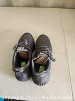 Top view of a pair of men's black running shoes with laces, placed side by side on a beige surface.