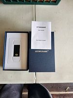 STTWUNAKE black USB stick in white tray inside dark blue branded box on a table.