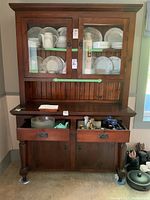 Front view of wooden buffet and hutch showing glass door cabinet, drawers open with kitchenware inside, and lower cupboards closed.