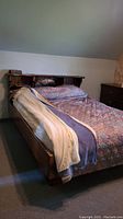 Front view of bed with bedding, showing headboard with shelves and mirror, plus part of mattress and quilts.