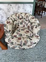 View of tub-style upholstered chair showing overall shape and geometric pattern upholstery