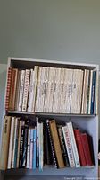 Shelf of multiple hardcover books including Better Homes and Gardens cookbooks, some with white spines.