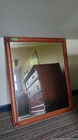 Full view of the wood framed beveled wall mirror reflecting surrounding furniture and walls