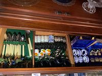 Drawer showing a variety of napkin rings in different materials and boxes, along with some cutlery with cream handles.
