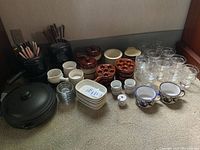 Photo of fondue pots, fondue forks, soup bowls, escargot dishes, seafood dishes, and glass ramekins arranged together