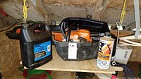 Full kit on shed shelf: chainsaw, case, lube jug and fuel can