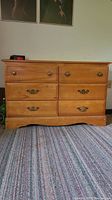 Front view of the wood dresser showing six drawers with copper color drawer pulls, rectangular shape, finished natural wood.
