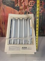 Front view of Alisun 429 S ultraviolet lamp showing 4 bulbs inside cream plastic casing with power cord wrapped around.