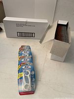 Two white boxes containing multiple blue blister packs of Tek Floss Picks, one box opened showing packs upright inside