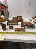 Wide view of the entire dollhouse furniture set including table, chairs, sofa, coffee table, ottoman, rocking chair, and framed picture