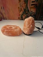 Image of Himalayan salt lamp and salt candle holder on surface, showing lamp's rough crystalline texture and base.